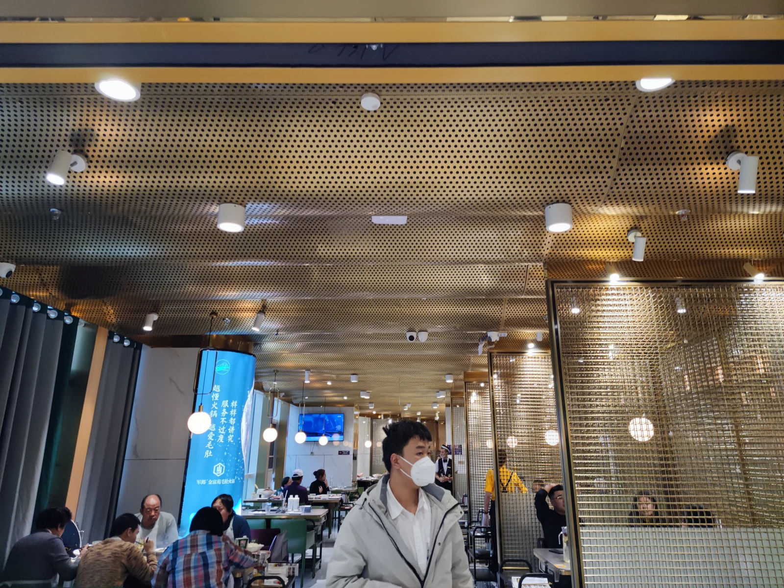 Gold-colored curved perforated metal ceiling and coordinated restaurant details