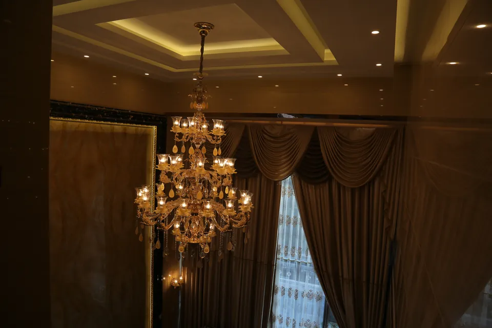 Finished villa interior with chandelier, ceiling details and full-height drapery.