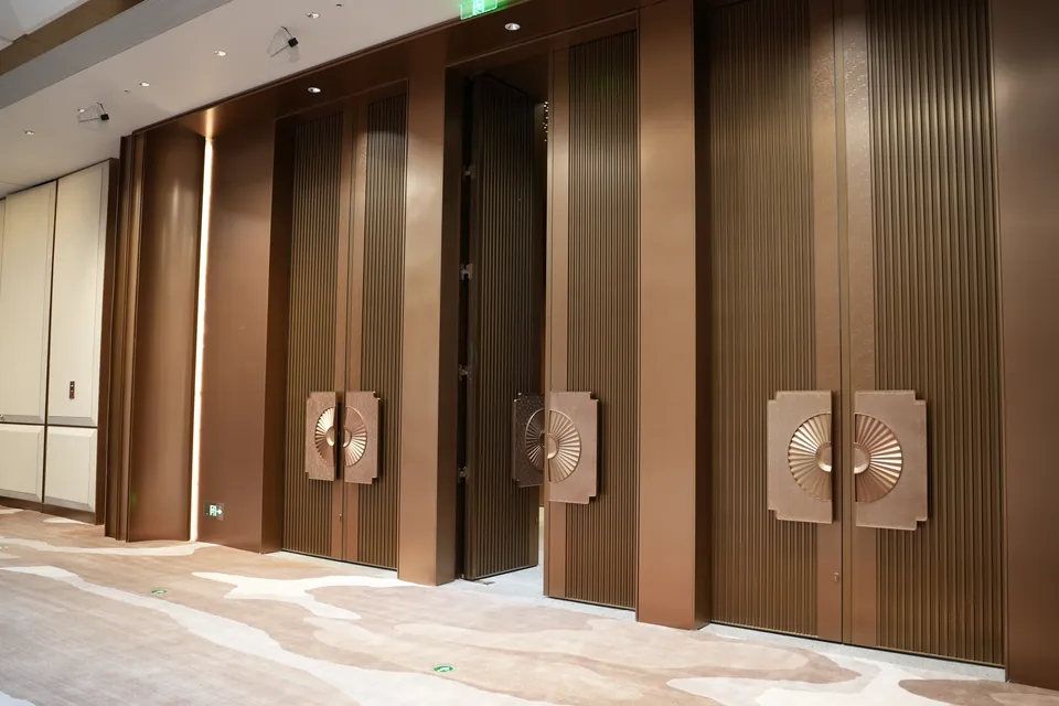 Row of completed bronze-toned event hall doors at the Shantou convention center.