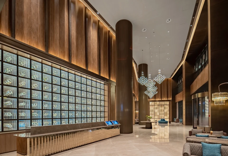 Completed hotel lobby with an illuminated glass-block feature wall, reception counter and lounge seating.
