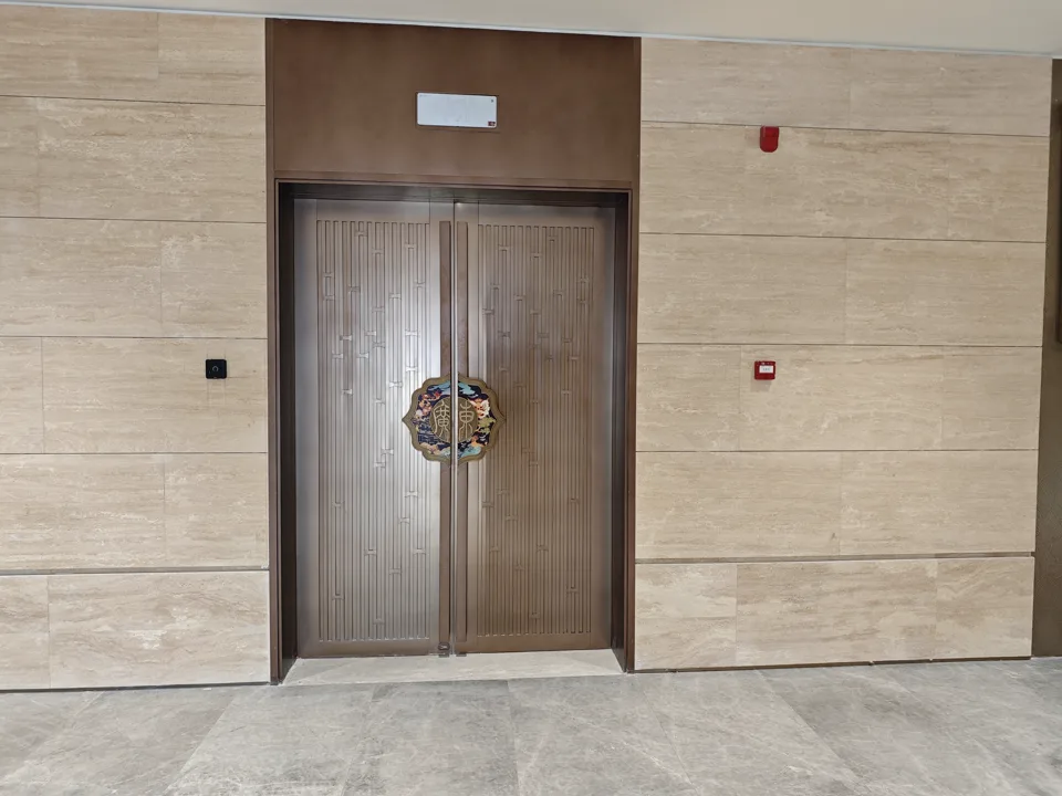 Completed bronze-toned double doors and stone wall at Guangdong Olympic Sports Center.