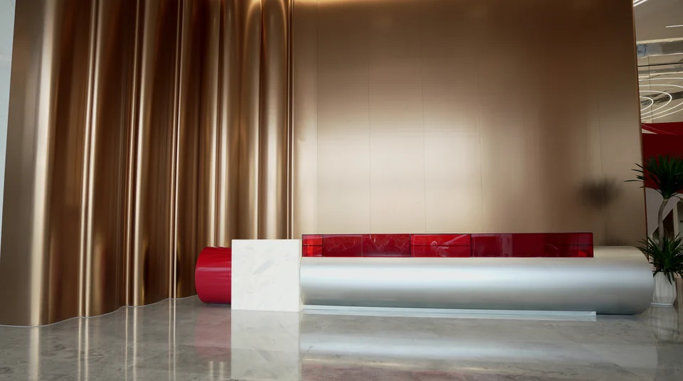 Completed reception area with a curved counter, a red accent and metal-toned wall surfaces at Yunan Office Building, Guangzhou.