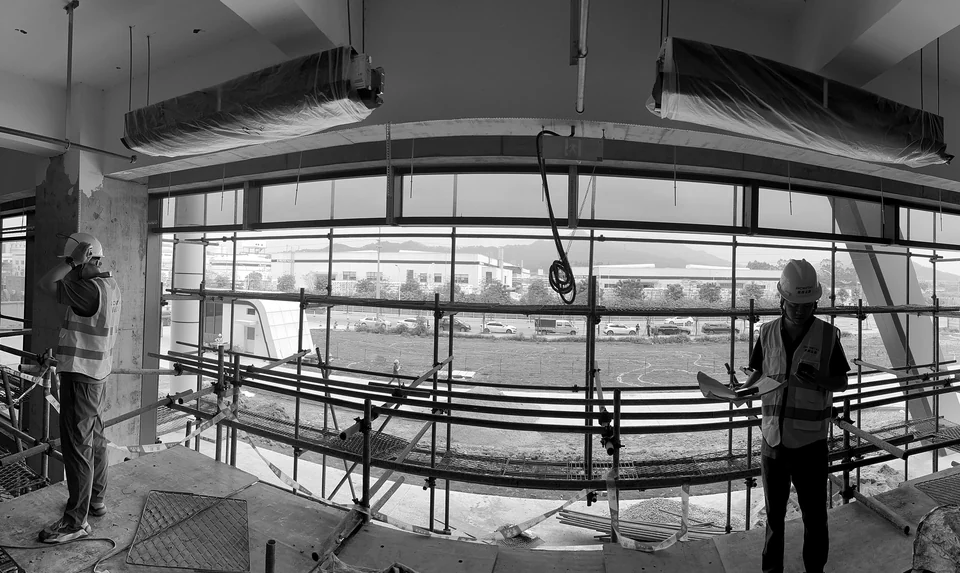 On-site installation view with workers, scaffolding and an unfinished ceiling at Yunan Office Building, Guangzhou.