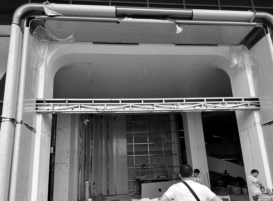 On-site installation view of a rounded entrance portal with workers and lifting equipment at Yunan Office Building, Guangzhou.