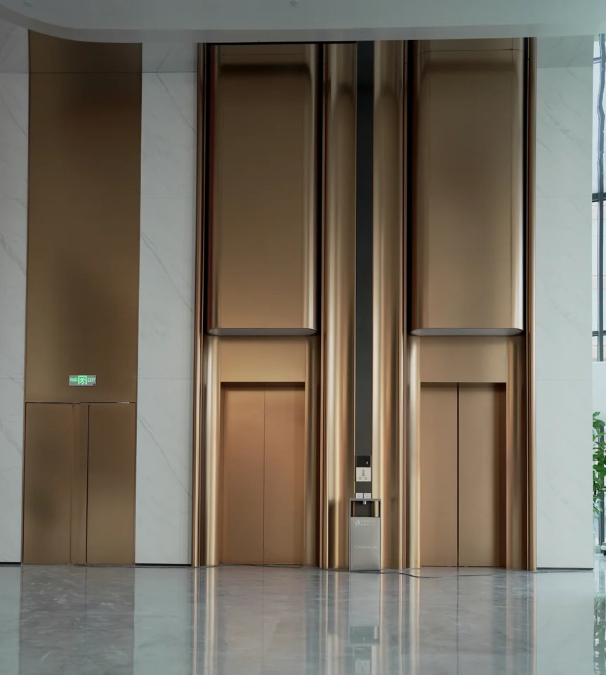 Completed lift hall with paired metal portals and the surrounding public interior at Yunan Office Building, Guangzhou.