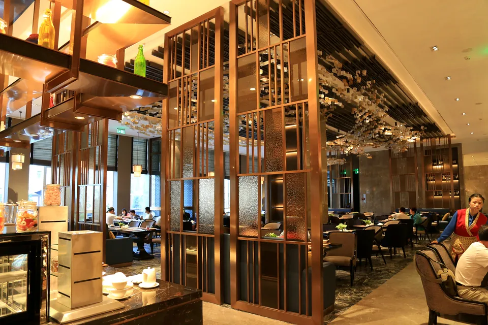 Champagne-bronze metal and textured-glass divider separating service and dining zones