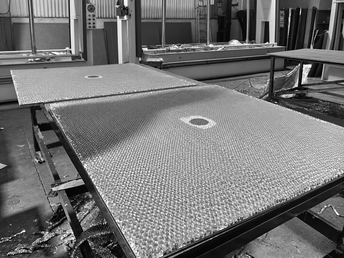 Honeycomb core sheets prepared on workshop tables, with the original circular openings visible.