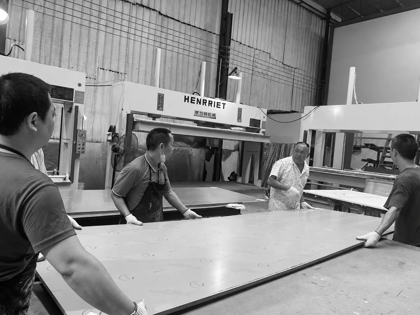 Workers handling a large panel together at the workshop table.
