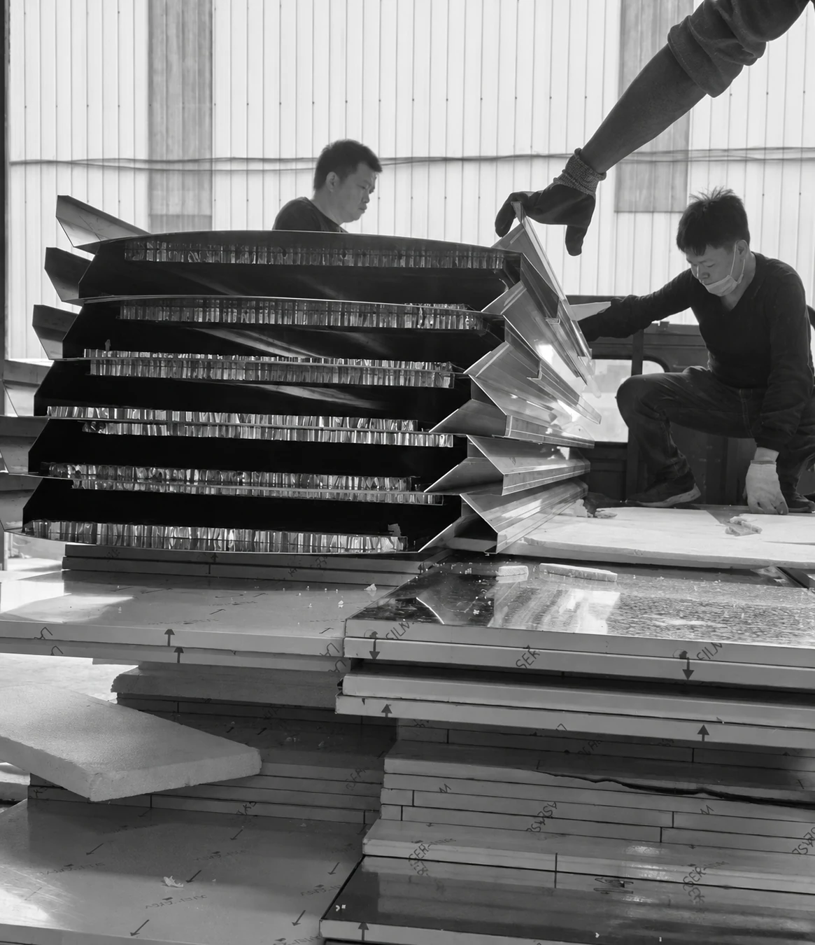 Panel edges and workers organizing stacked panels in the workshop.