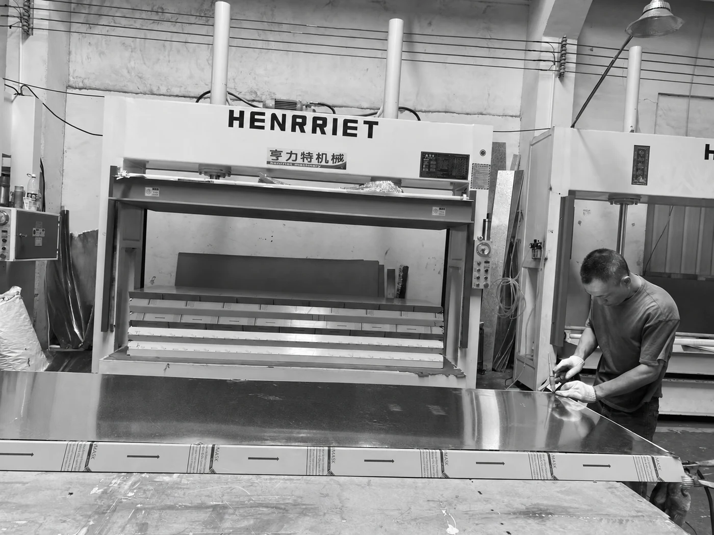A worker beside a metal panel and the workshop press.