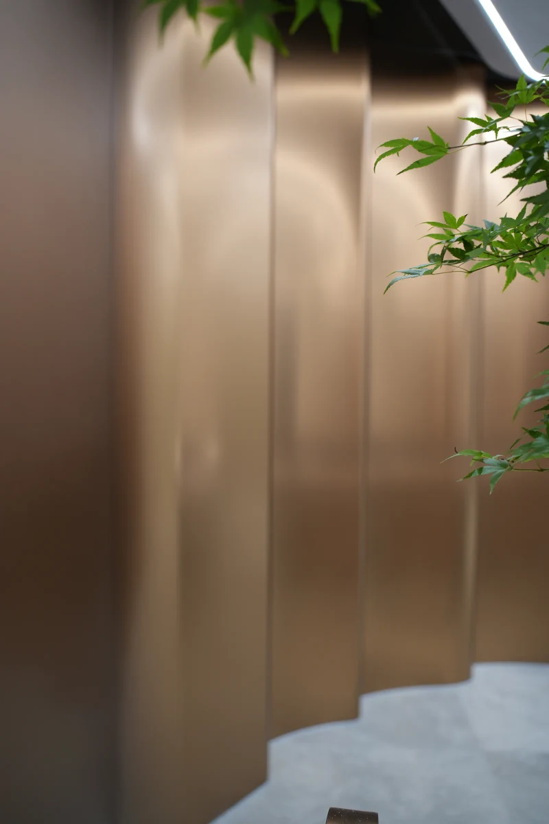 Close view of curved bronze-toned wall panels and vertical joints at Yunan Office Building, Guangzhou.
