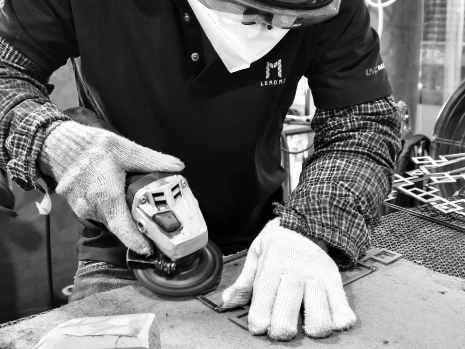 Black-and-white photograph of an LMC worker grinding a metal surface