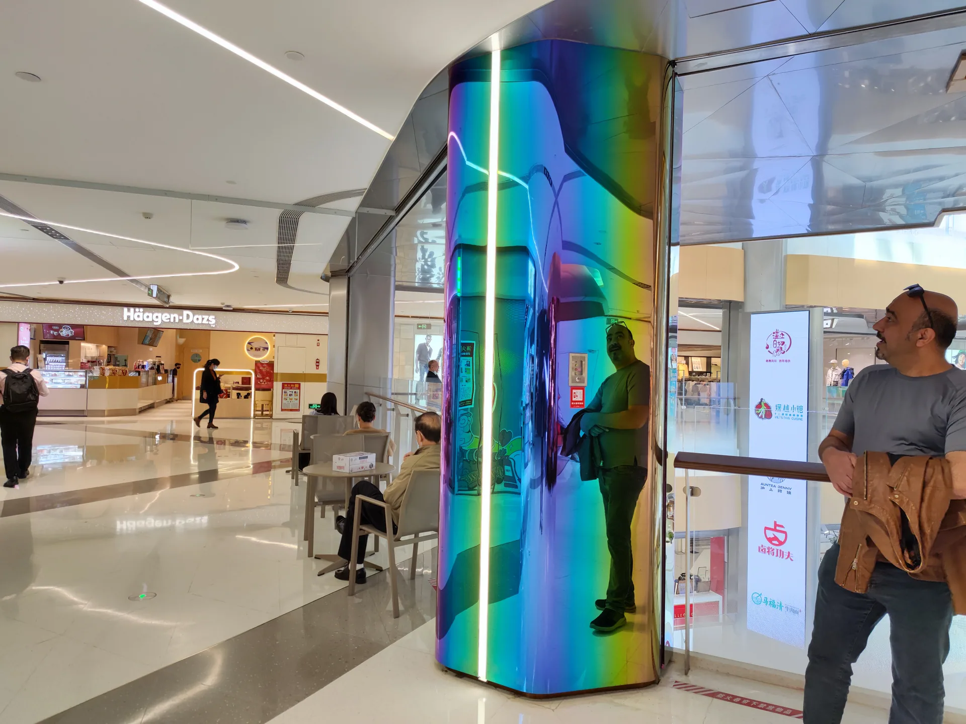 Site photograph of a colorful reflective curved column and a vertical LED strip