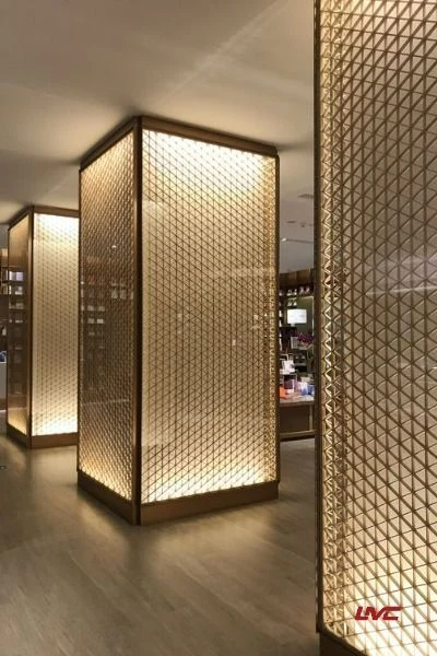 Square columns wrapped in geometric metal mesh with warm illumination, retaining the original LMC watermark