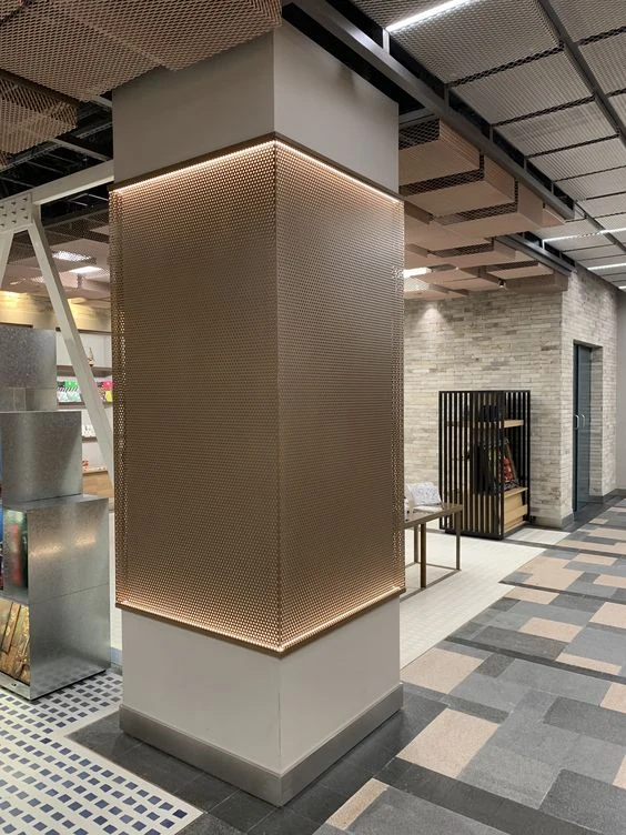 Perforated metal wraps the middle of a square column with warm edge lighting and white sections above and below