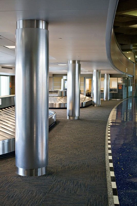 Silver brushed round column cladding with circular top and base details in a public interior