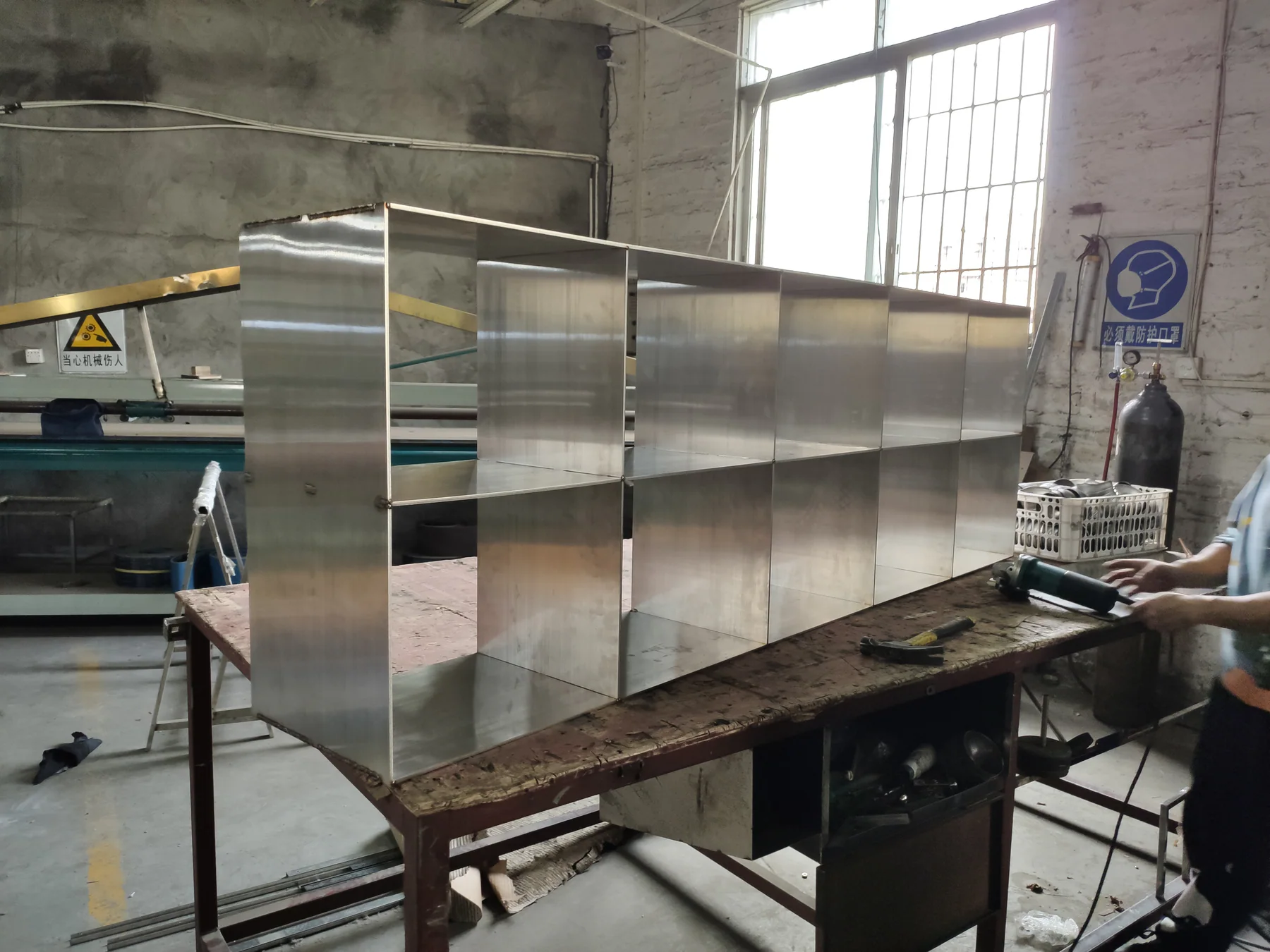Solid stainless steel sheet cabinet with open shelves, photographed in the workshop