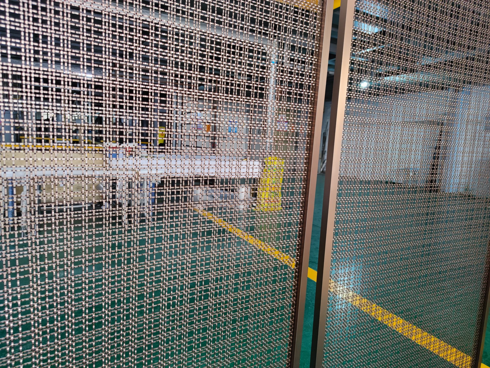 Close workshop view of framed architectural metal mesh screen panels