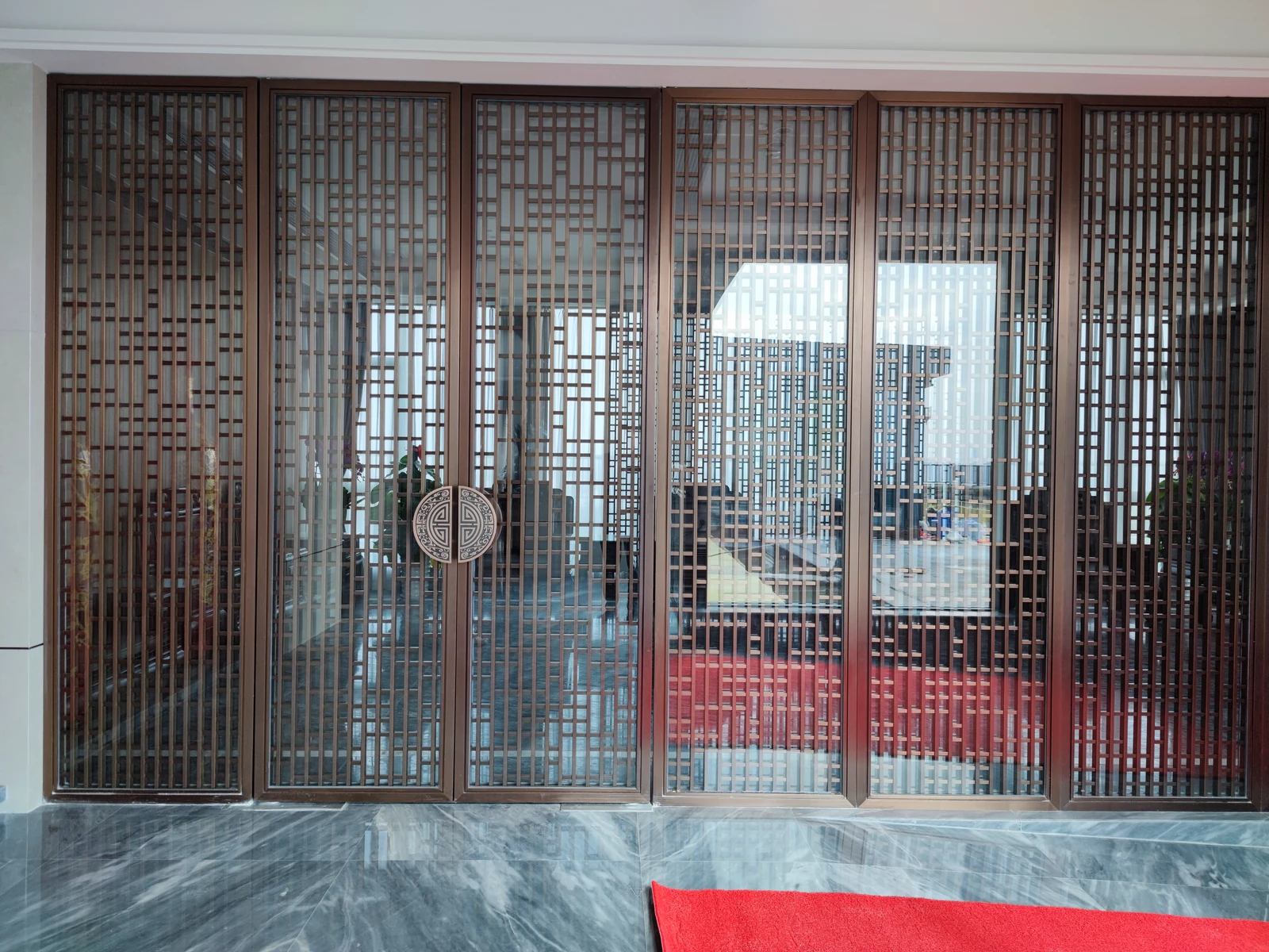 Full-height framed metal grille and glazed screen installed in an office interior