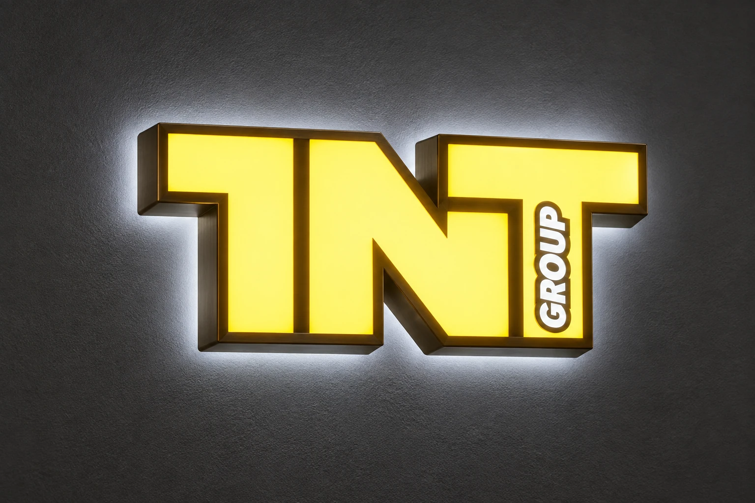 TNT GROUP sign showing colored illuminated faces and a surrounding halo